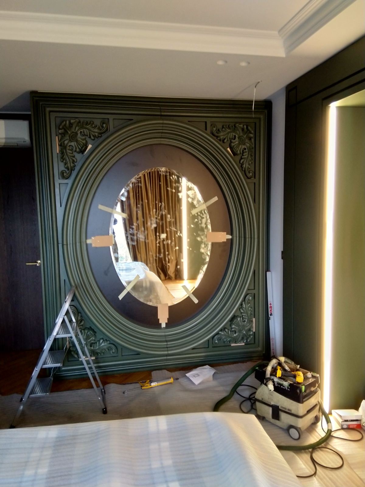 The oval mirror and carved surround being fitted