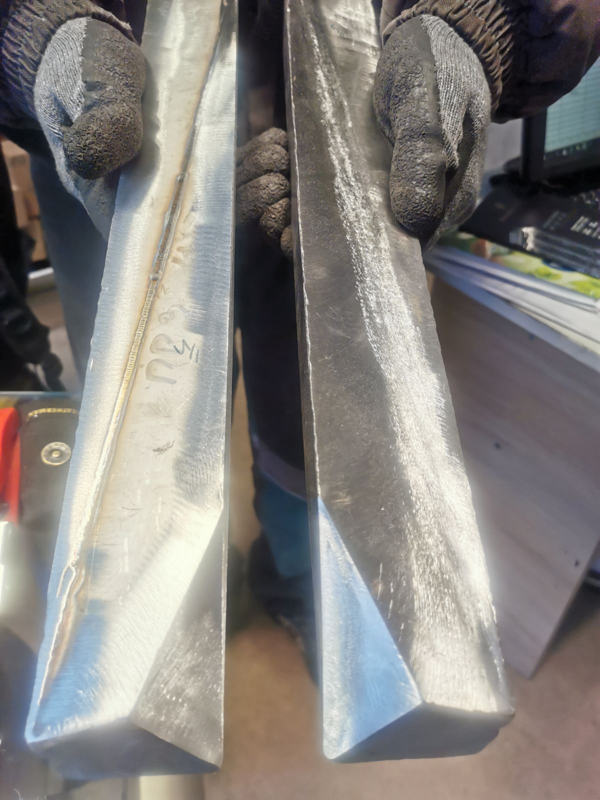 Two welded steel sections held in gloved hands