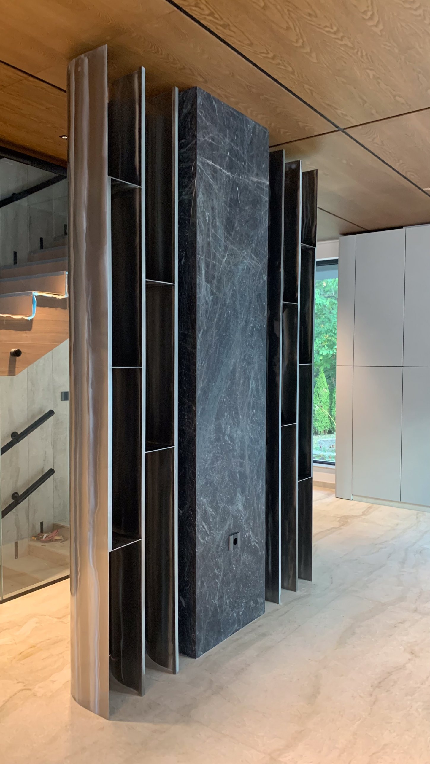 A dark stone column flanked by curved brushed-metal shelving