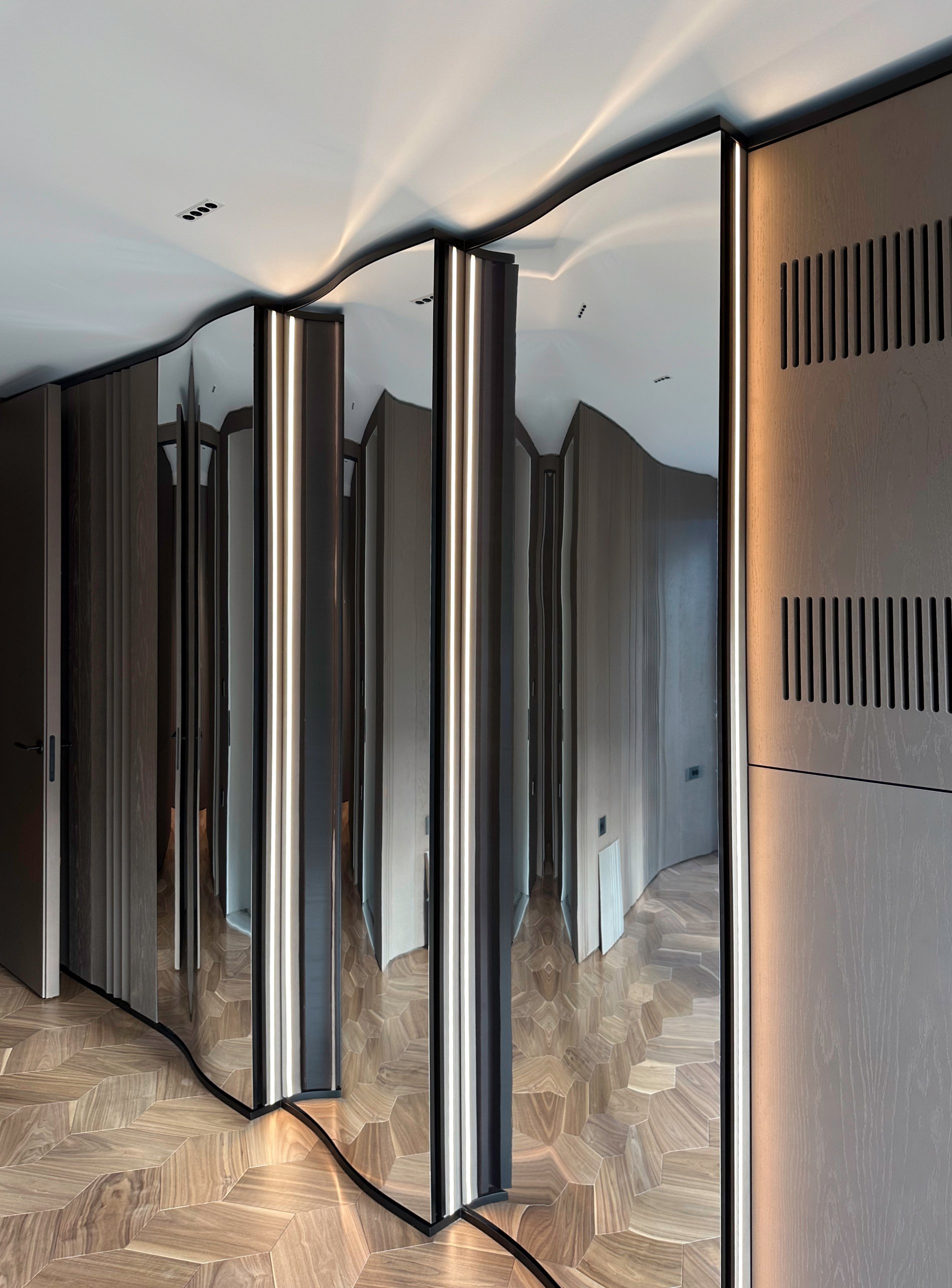 The undulating mirrored wardrobe with lit vertical joints