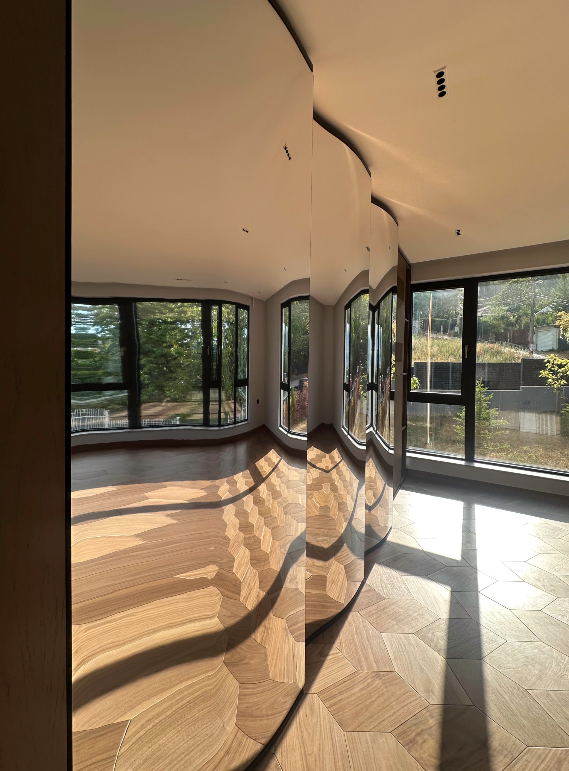 Sunlight and the timber floor rippling across the curved mirrors