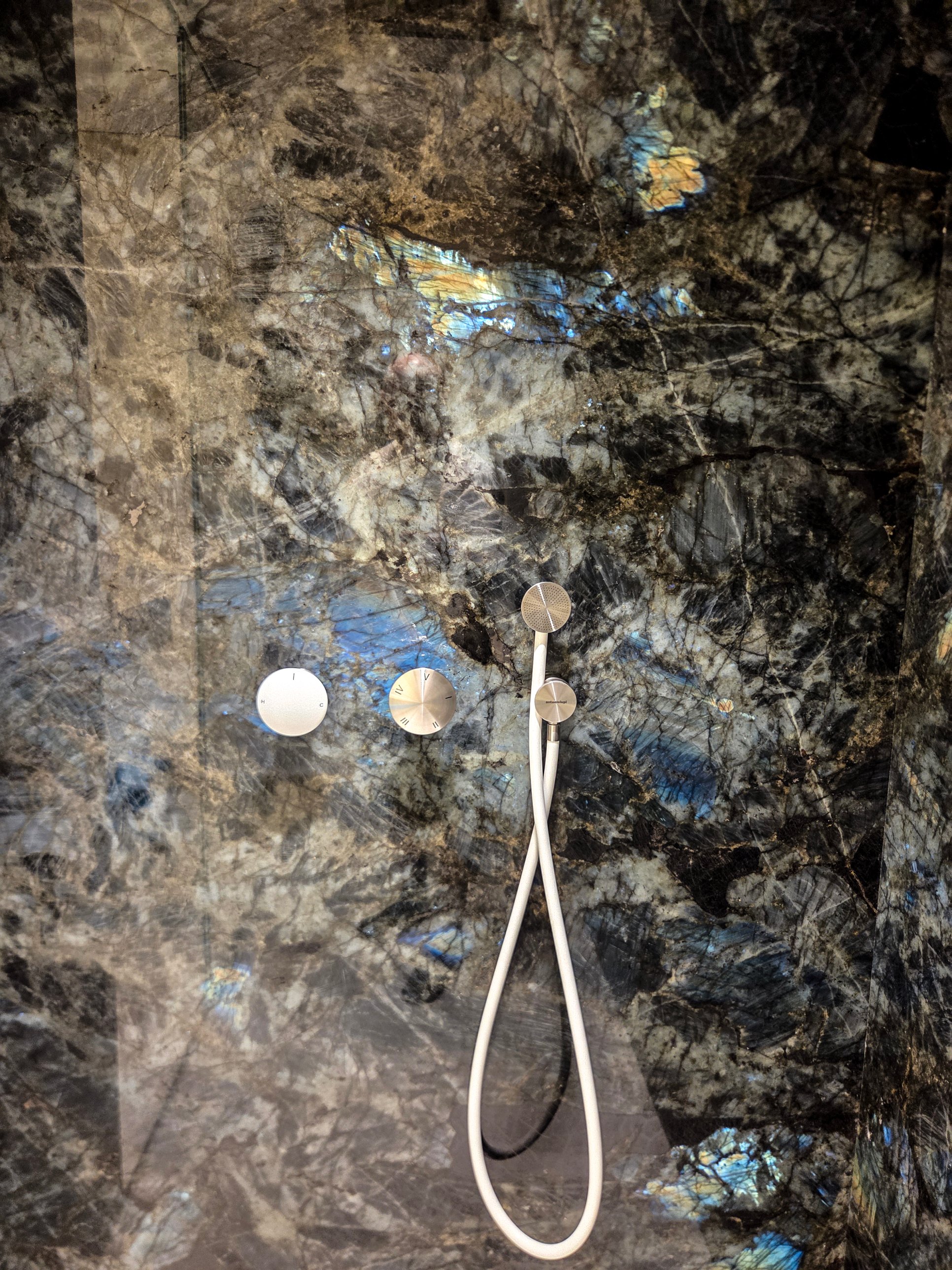 A shower wall of dark, richly patterned stone