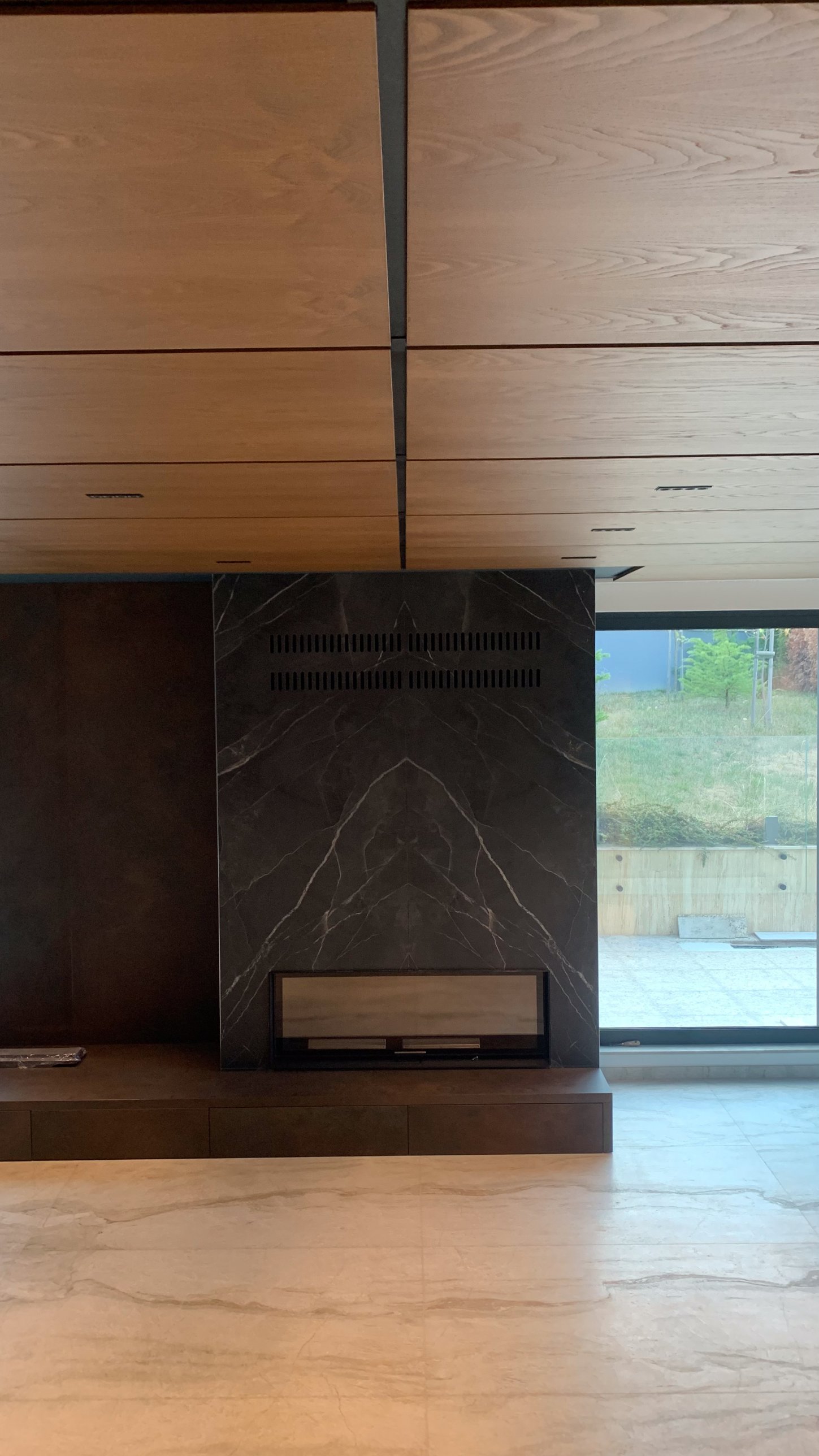 The dark stone fireplace beneath the timber ceiling, on site