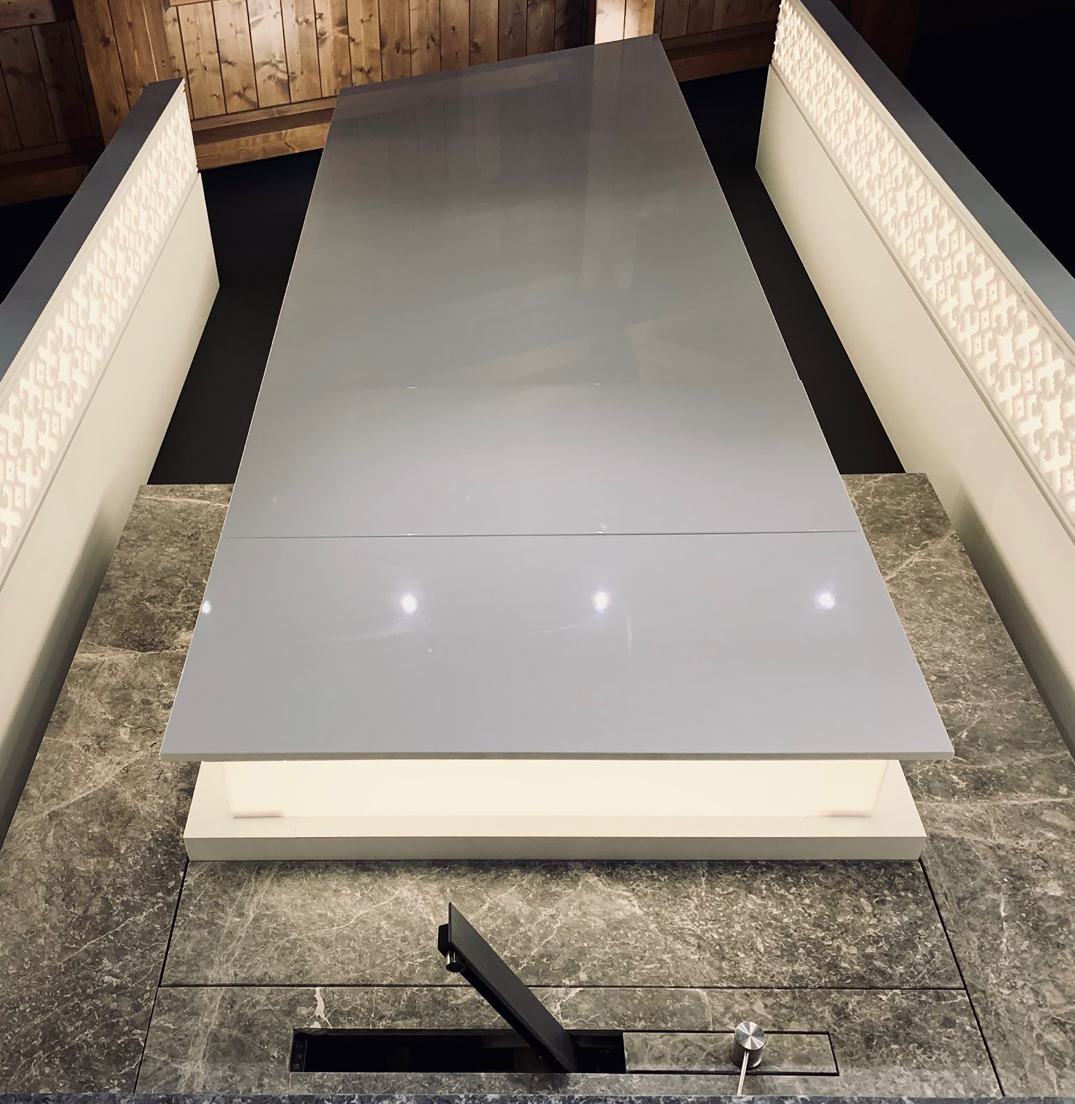 A gloss panel above the stone worktop between pattern-lit side panels
