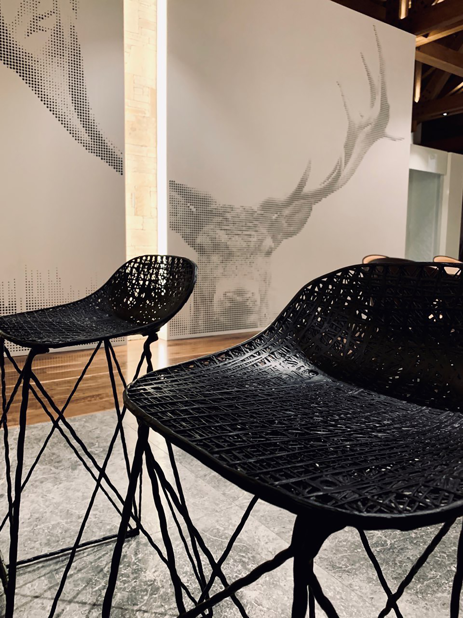 Black lattice bar stools before the perforated stag wall