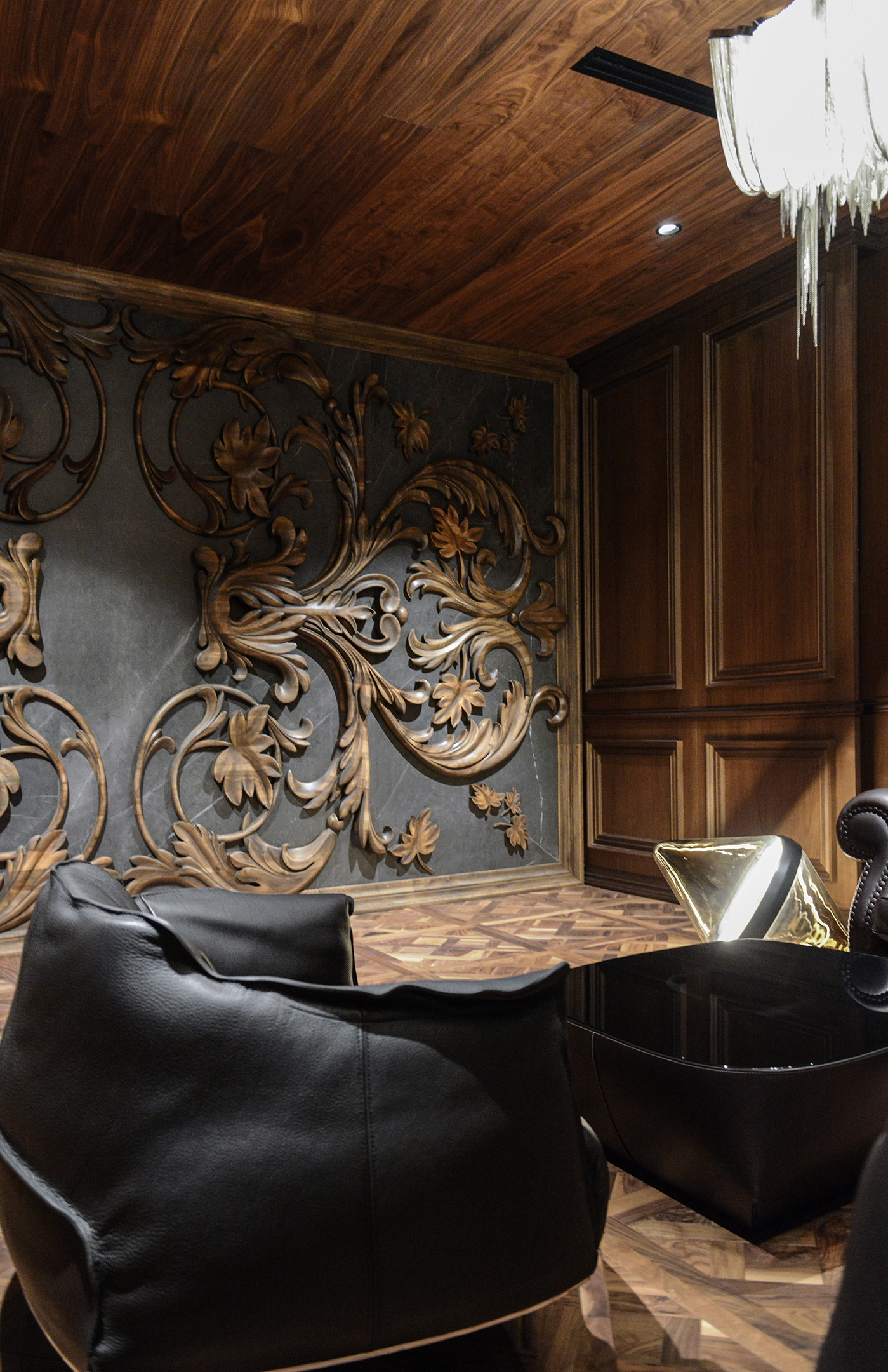 Carved walnut ornament on a dark stone wall, with walnut panelling and leather seating