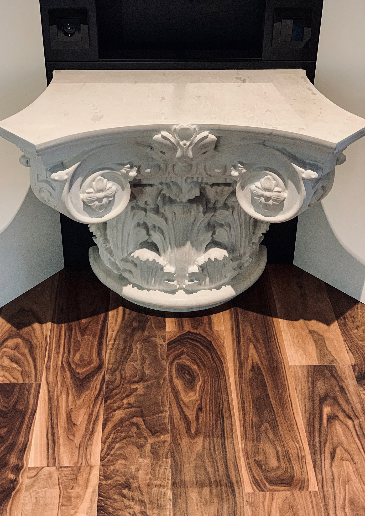 The carved capital console above the walnut floor