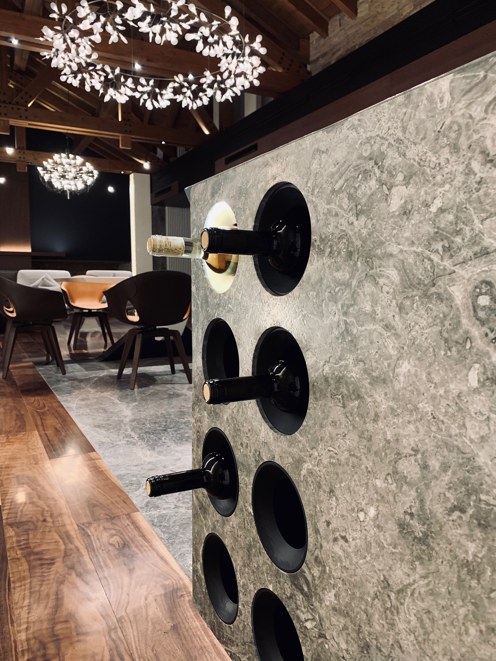 Circular bottle recesses cut into the end of the stone kitchen island