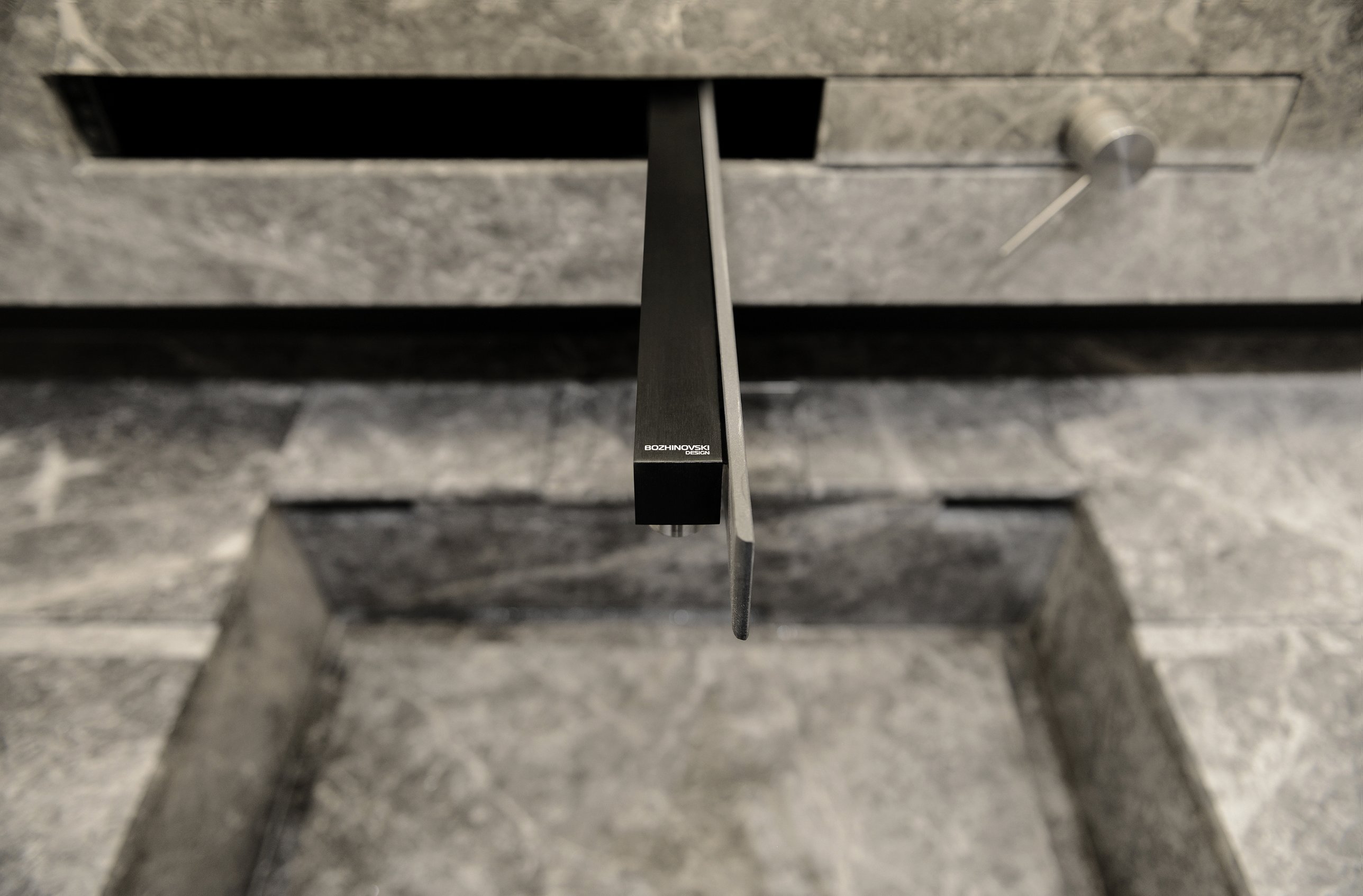 The slot-mounted black tap marked Bozhinovski Design above the stone sink