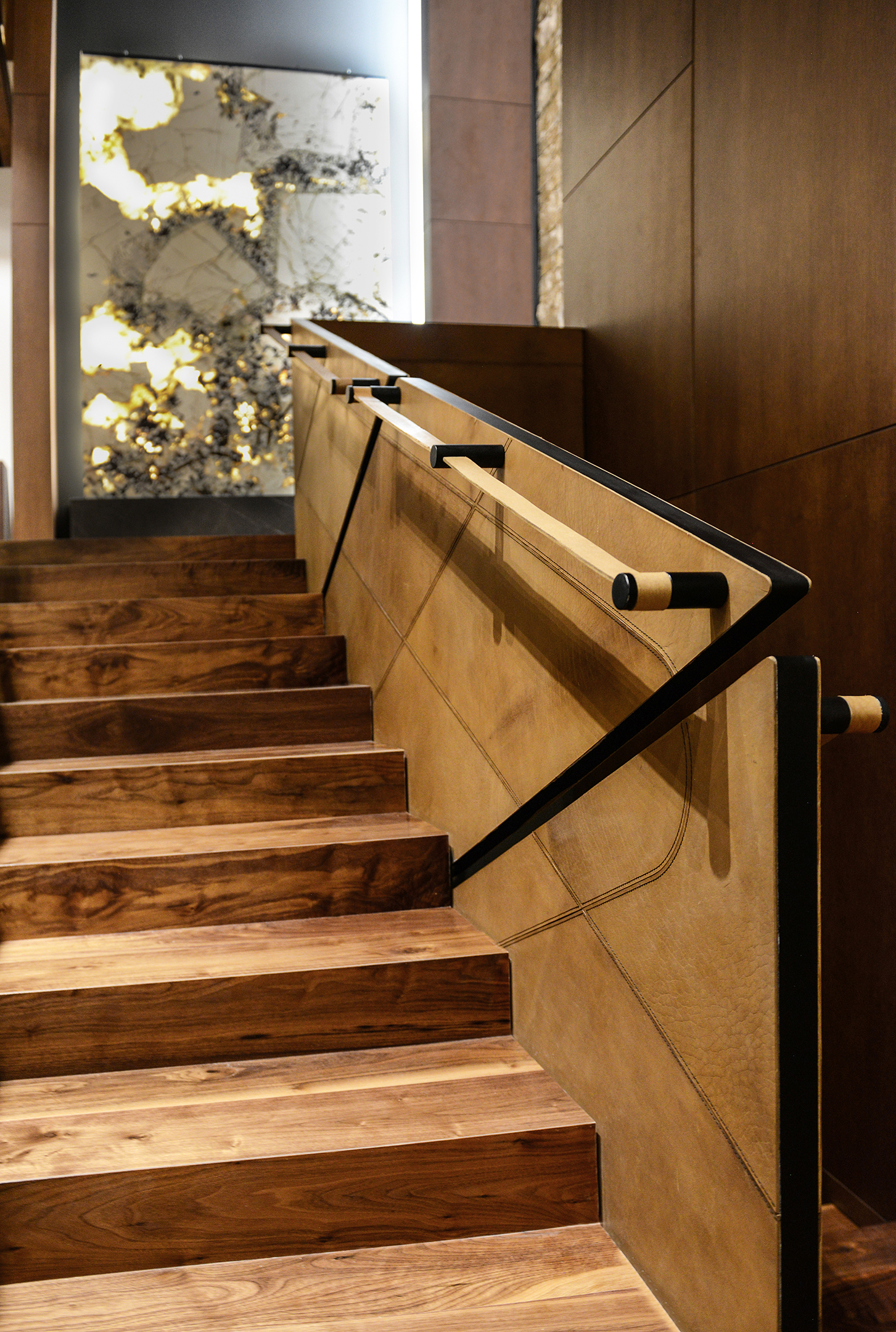Walnut stair with a stitched leather balustrade and timber handrail