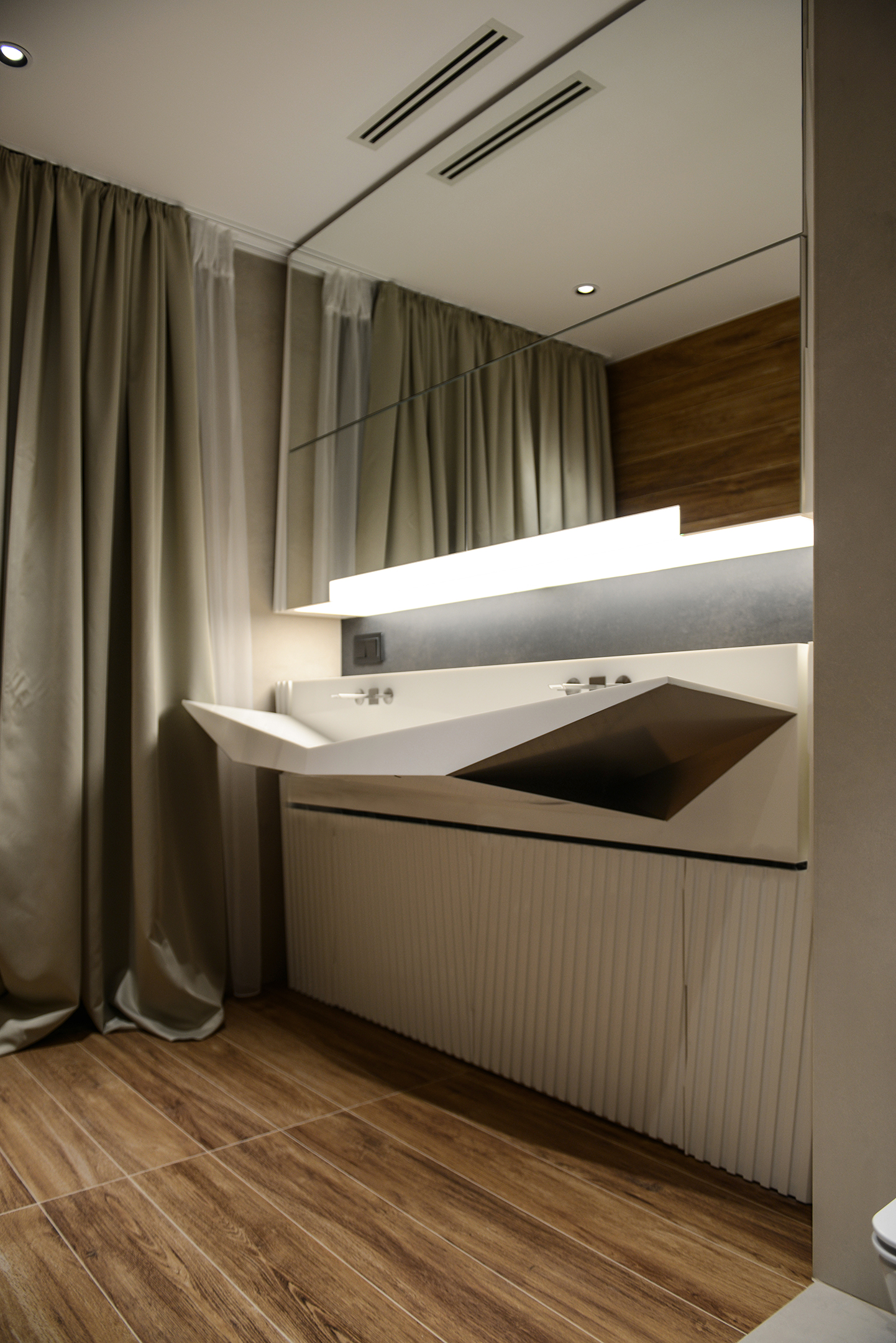 An angular white basin above fluted cabinetry