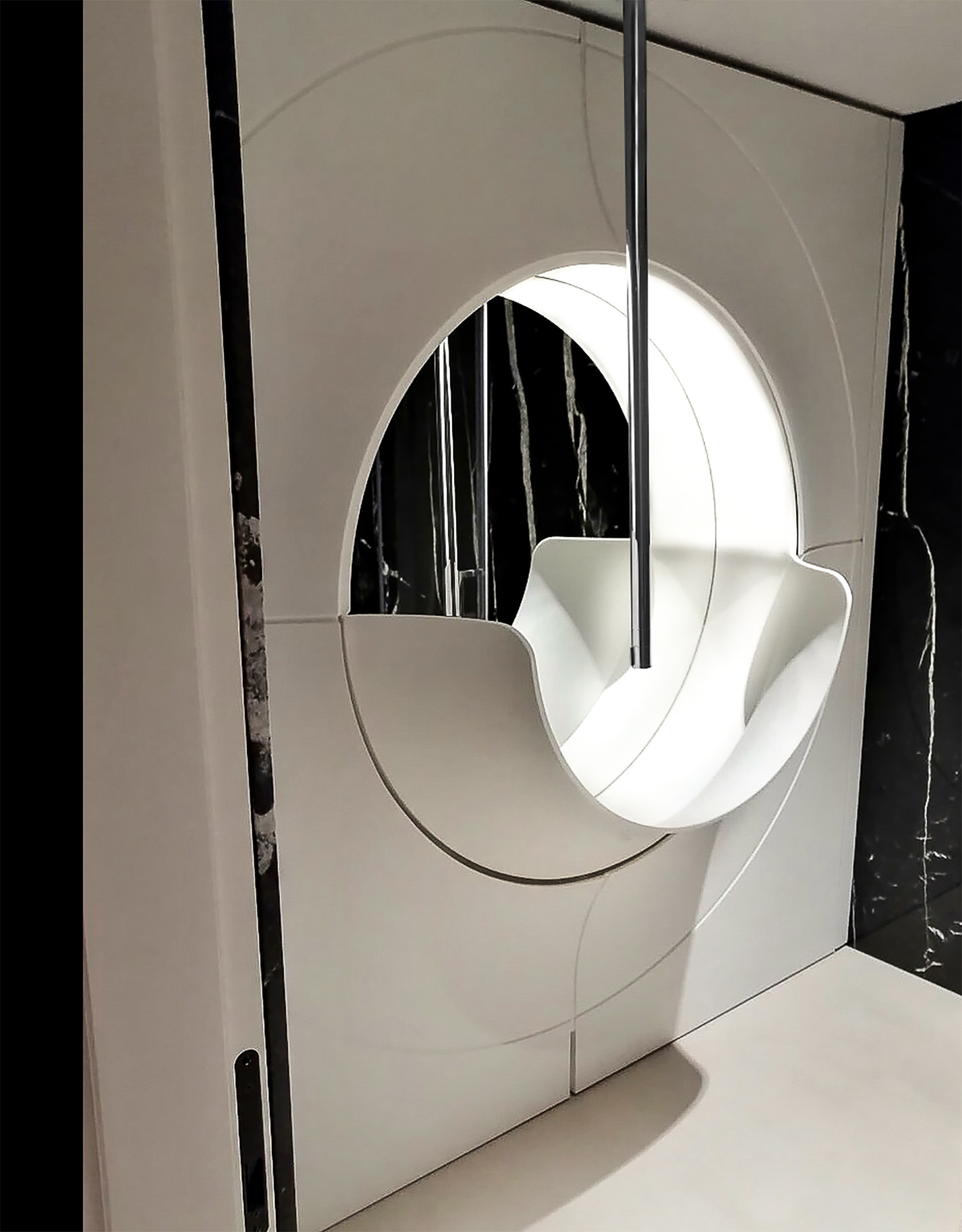 A sculpted circular basin set into a white wall panel