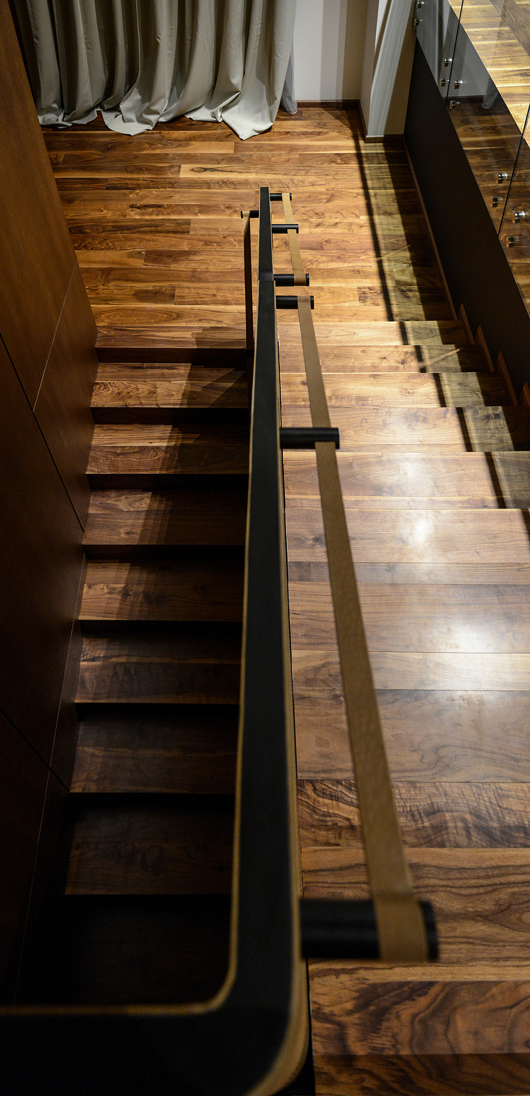 The walnut stair seen from above, with its leather handrail