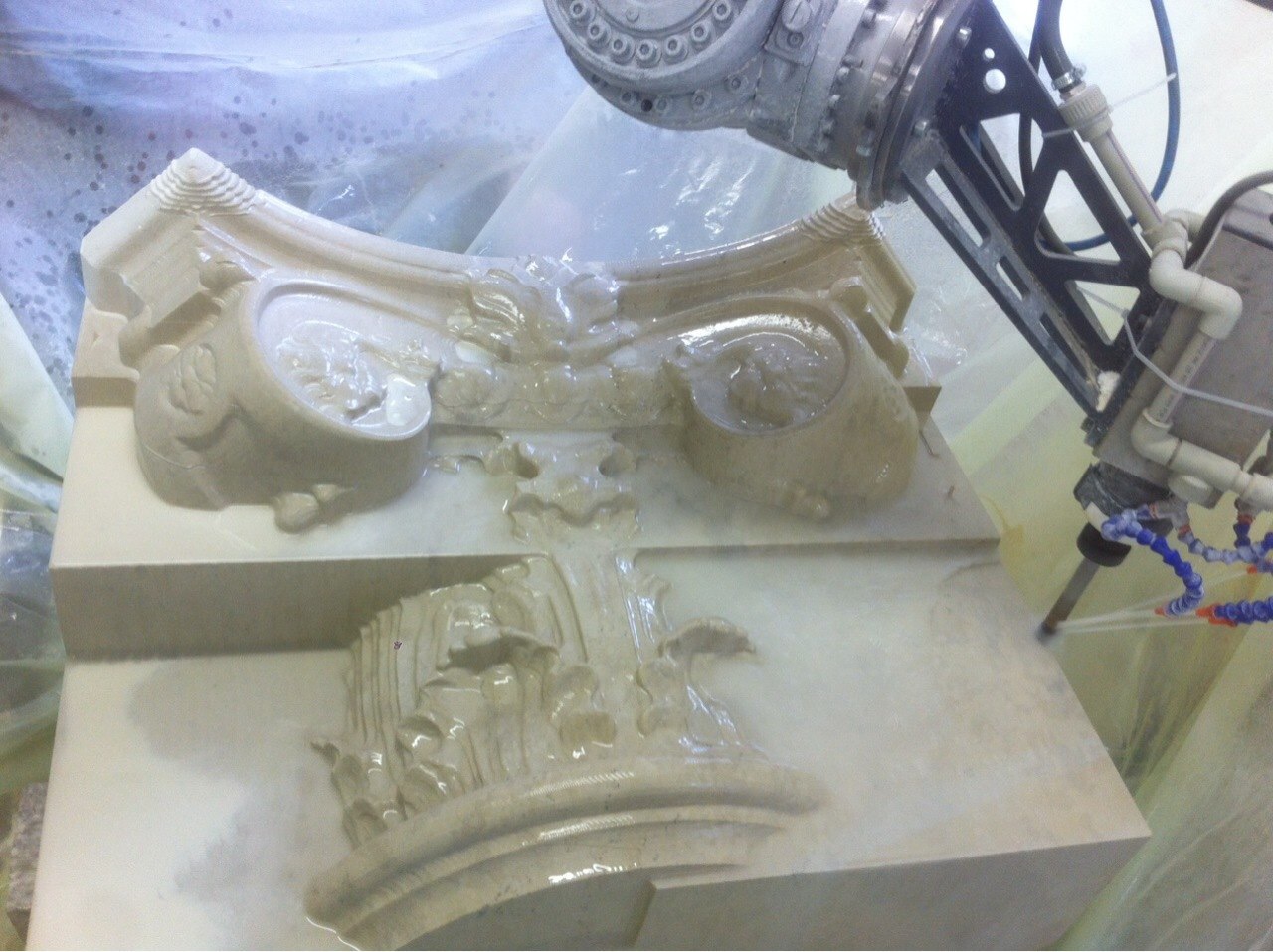 A robotic arm carving a classical capital in stone