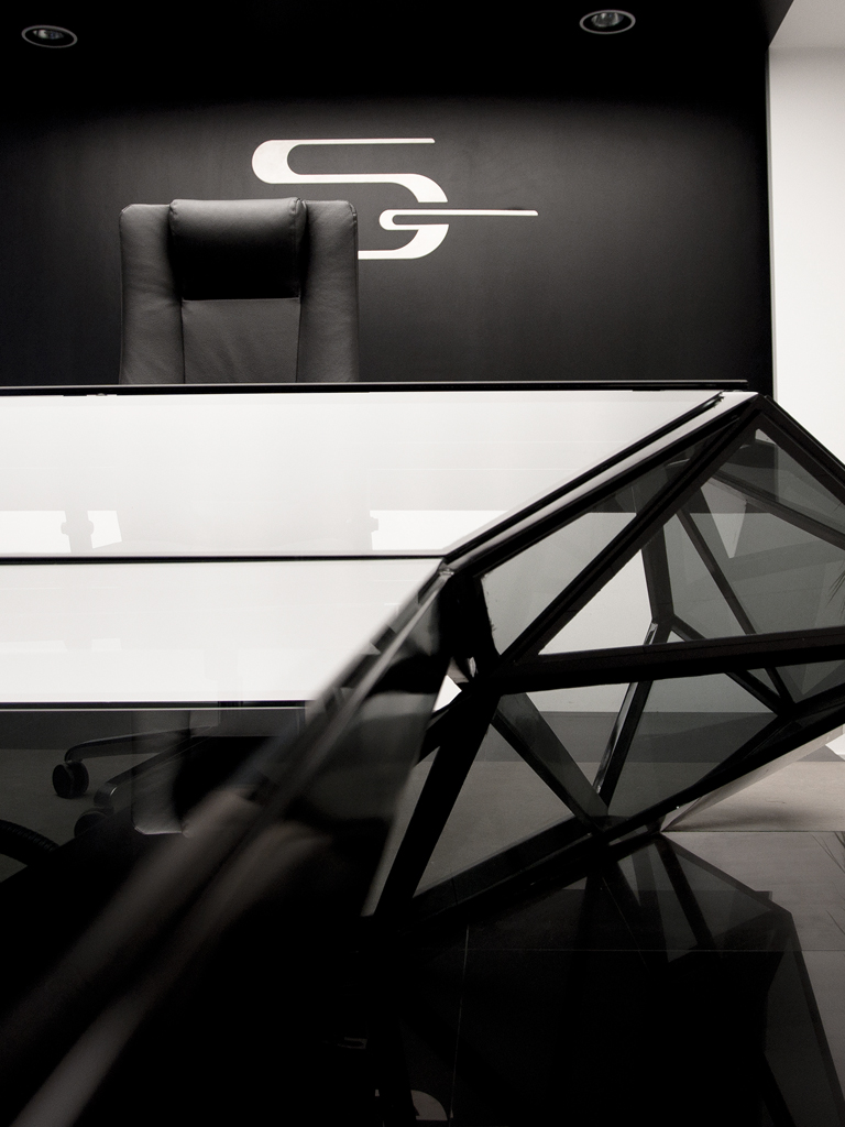 Close view of the glass-faceted desk before the executive chair and the company emblem