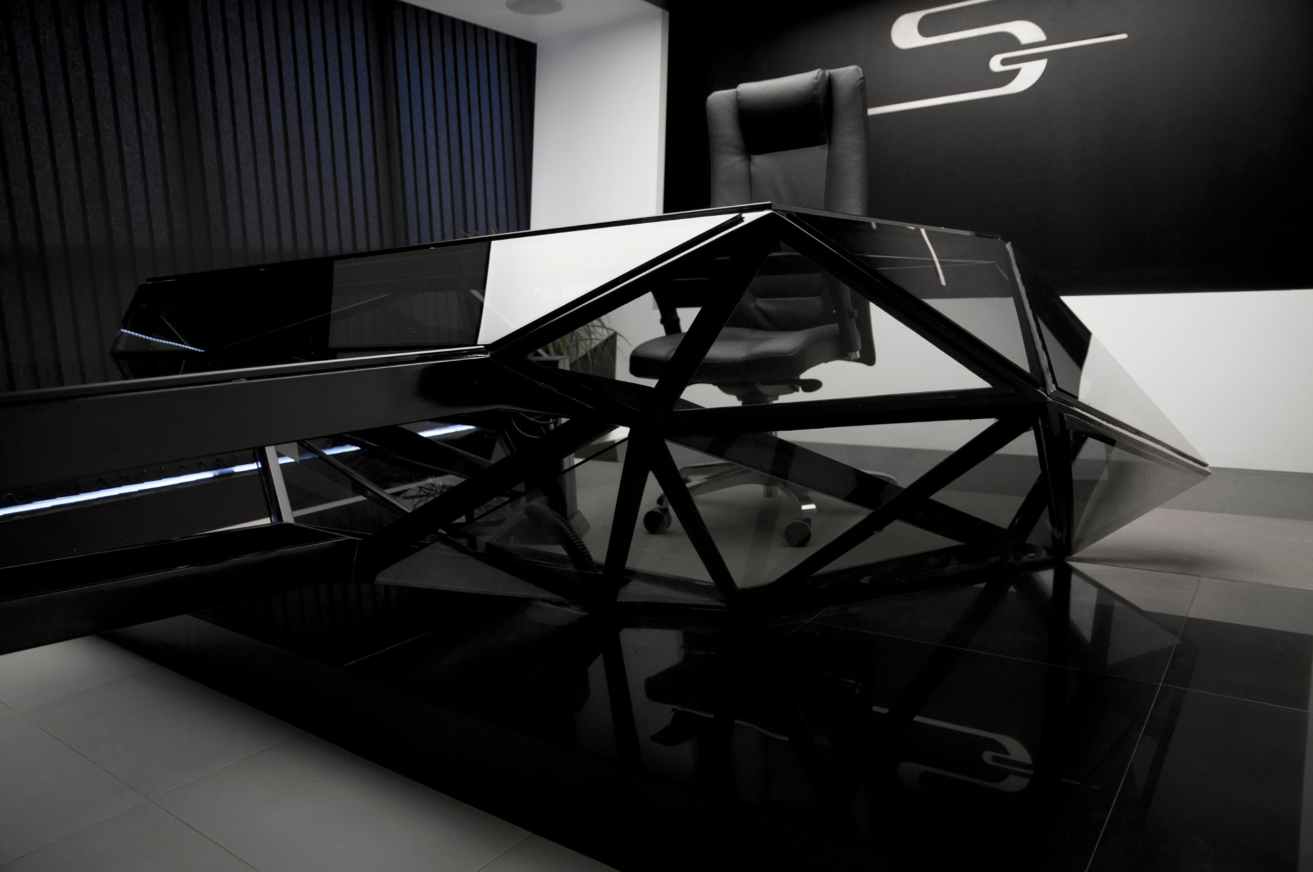 Black steel triangles framing smoked glass around the executive chair