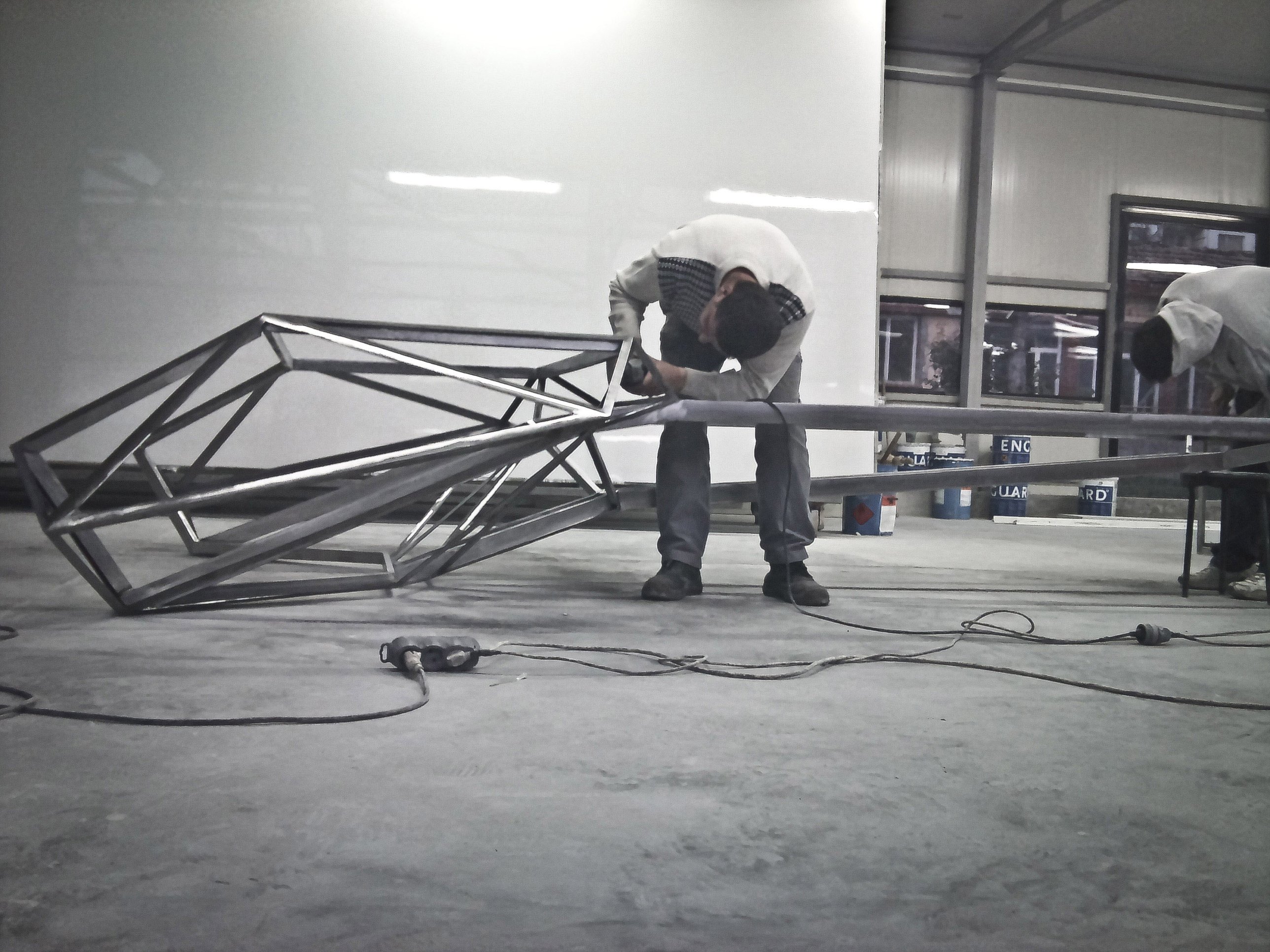 Grinding the welded steel frame of the desk in the workshop