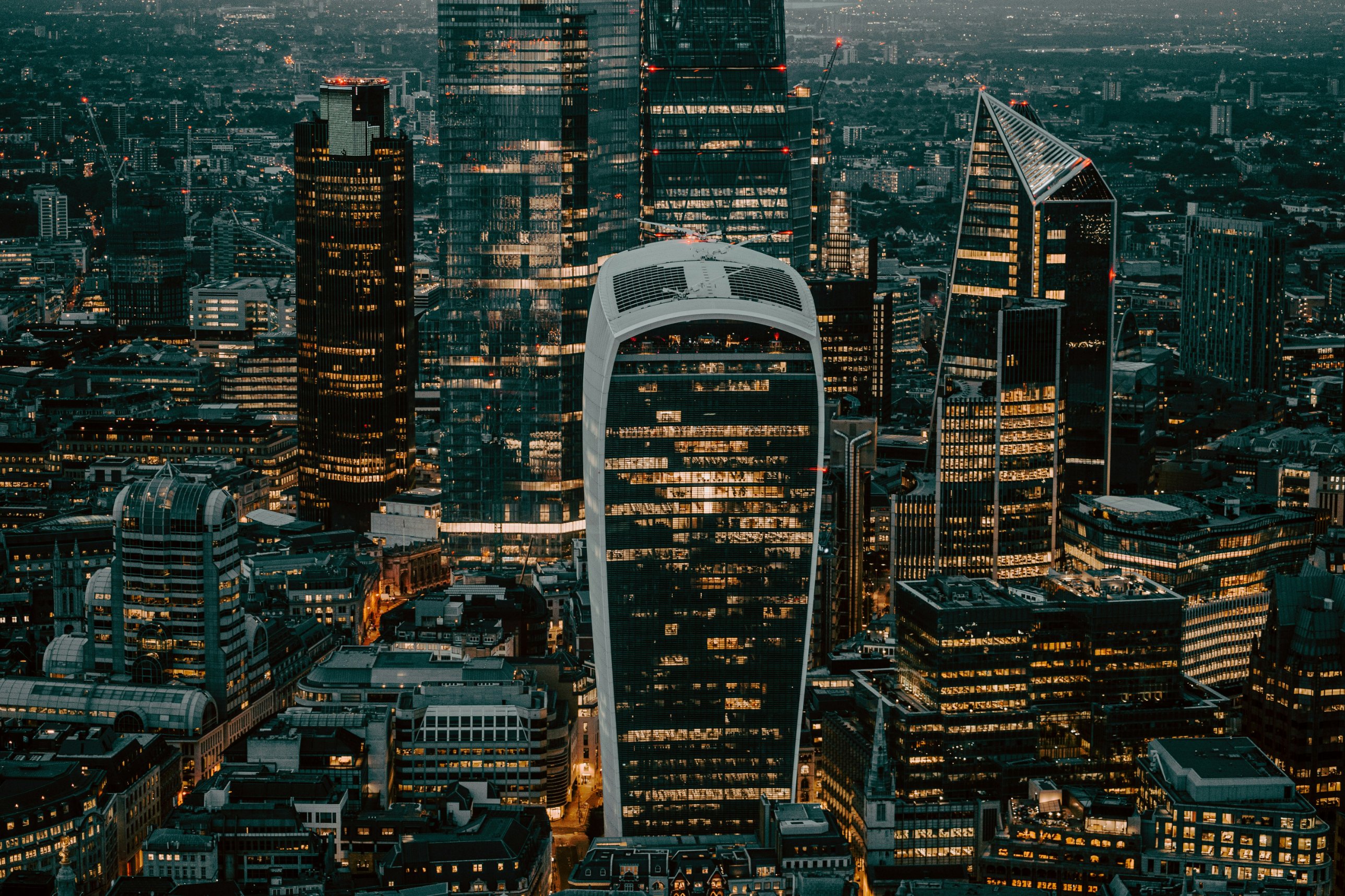 The City of London at dusk, its towers lit against the evening sky