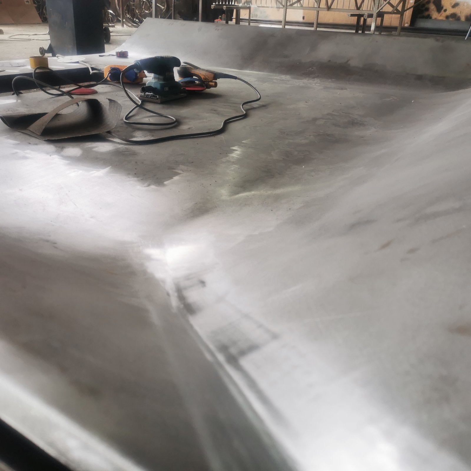 Sanding the curved steel surface of the fireplace